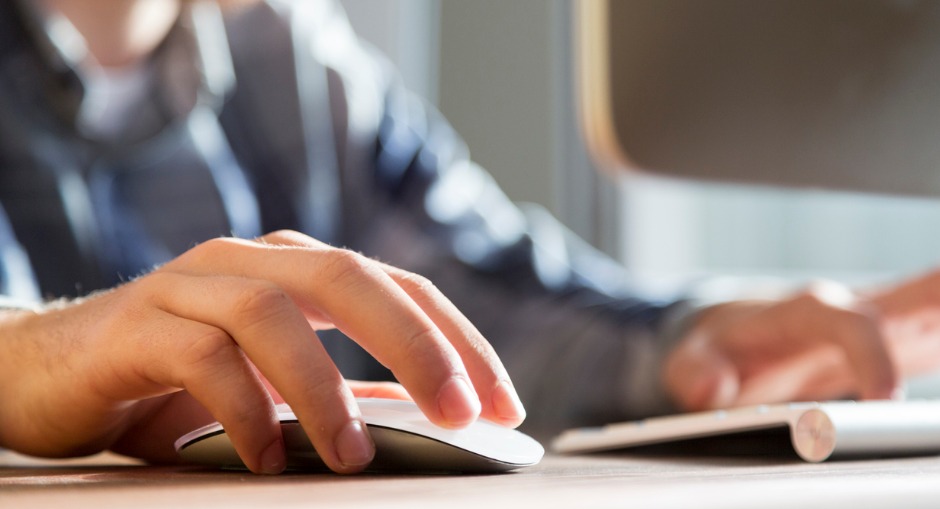 A hand using a mouse on a desk